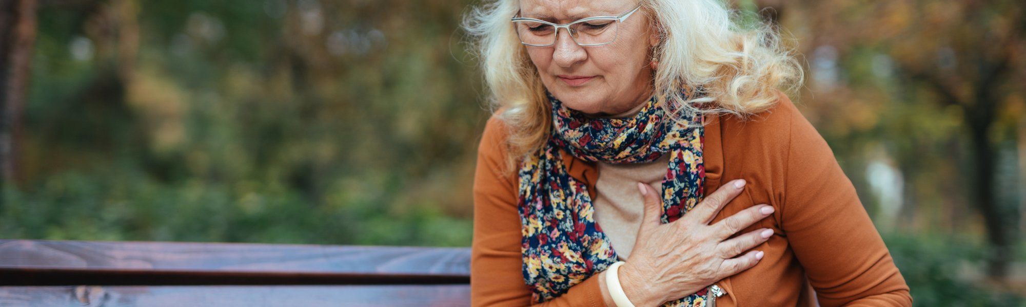 Elderly woman having chest pains or heart attack in the park