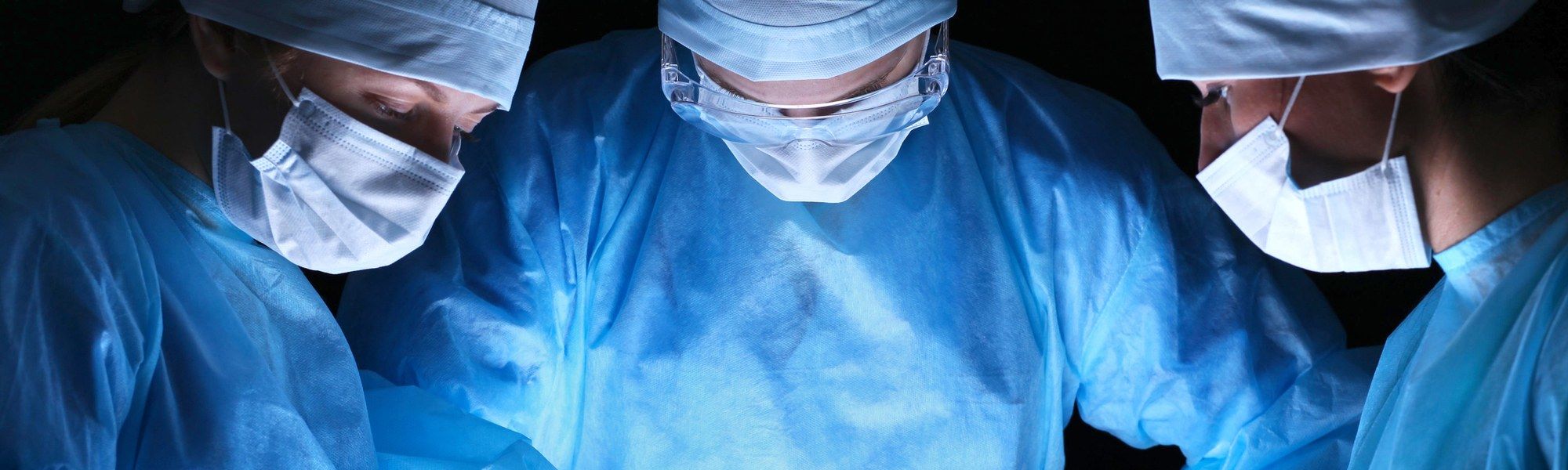 Group of surgeons in masks performing operation