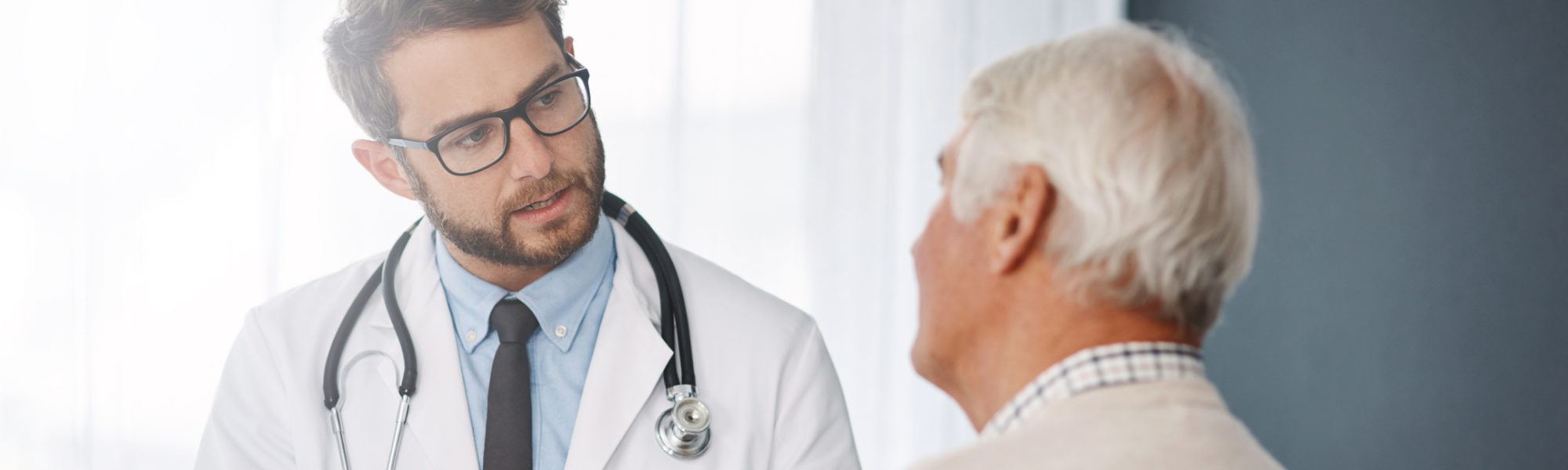 male doctor going through medical records with his senior male patient