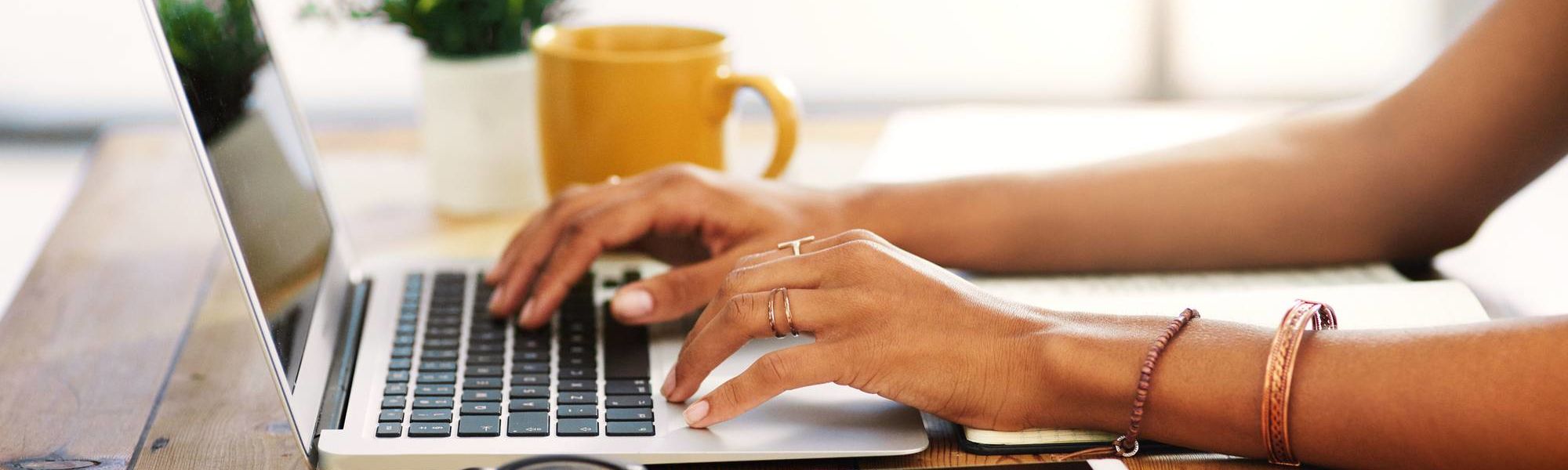 Woman's hands typing on a laptop