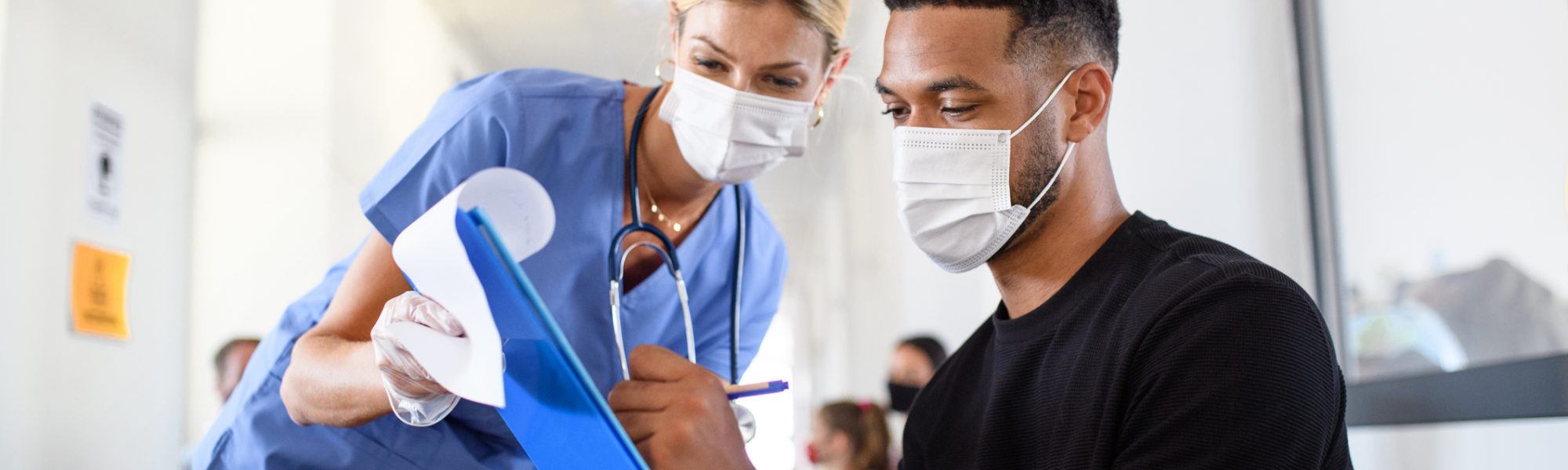 nurse and man with face masks going through paperwork